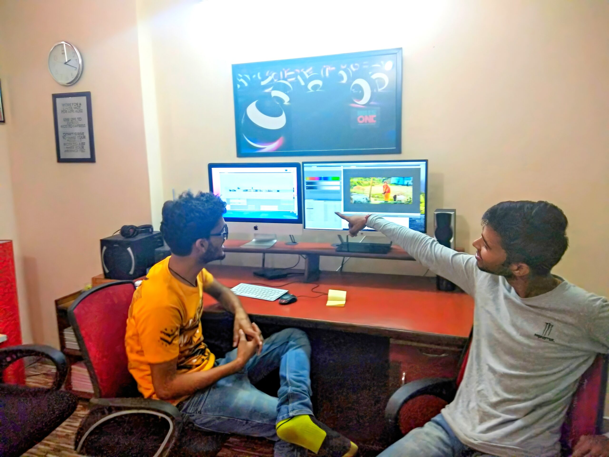 Payal Films lead photographer collaborating with editing team in Bihar office, reviewing wedding photos on dual monitors