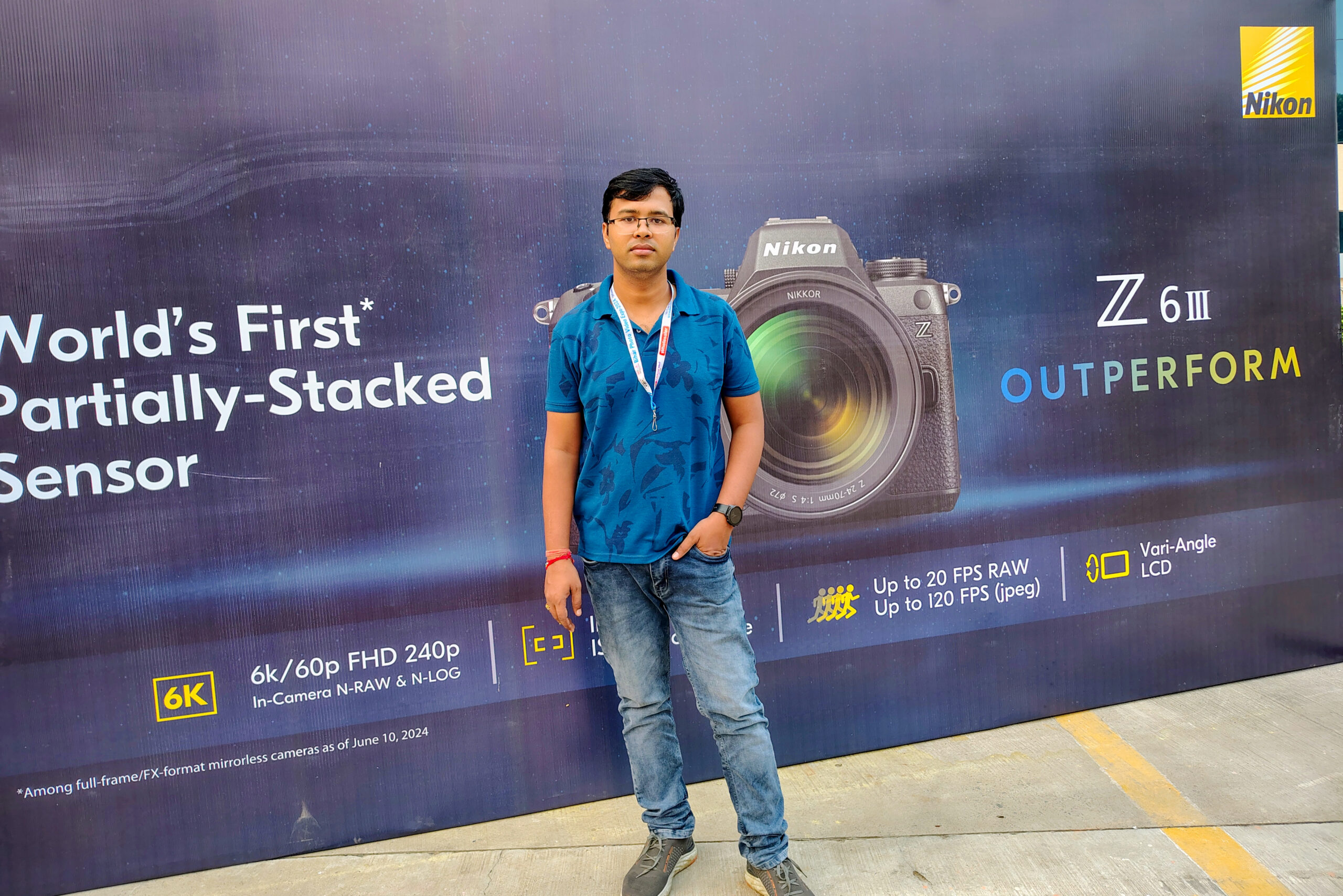 Payal Films wedding photography business owner standing in front of Nikon camera promotional backdrop at photography event in Bihar