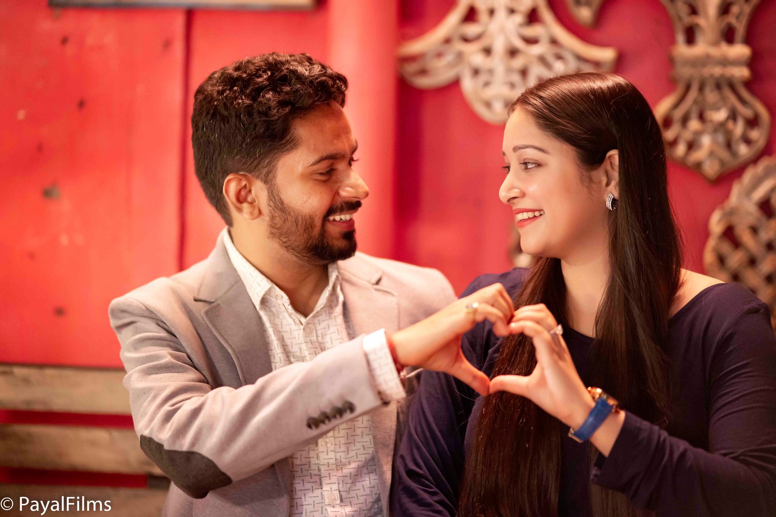 A romantic couple making a heart shape with their hands, captured by Payal Films in a cinematic portrait.