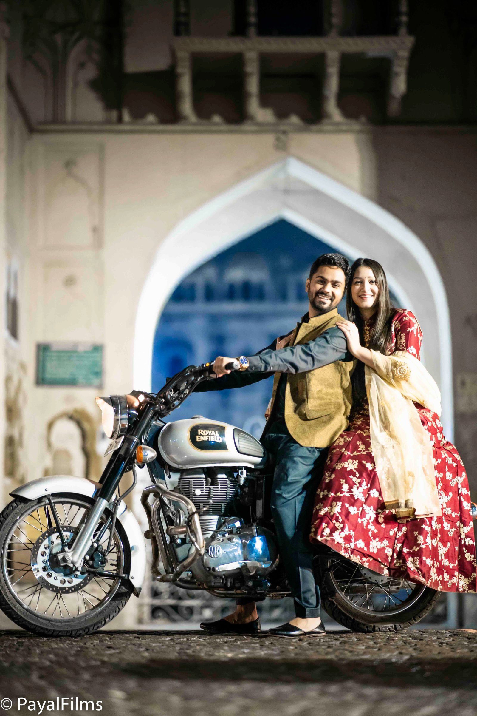 Couple posing on a Royal Enfield bike during pre-wedding shoot by Payal Films