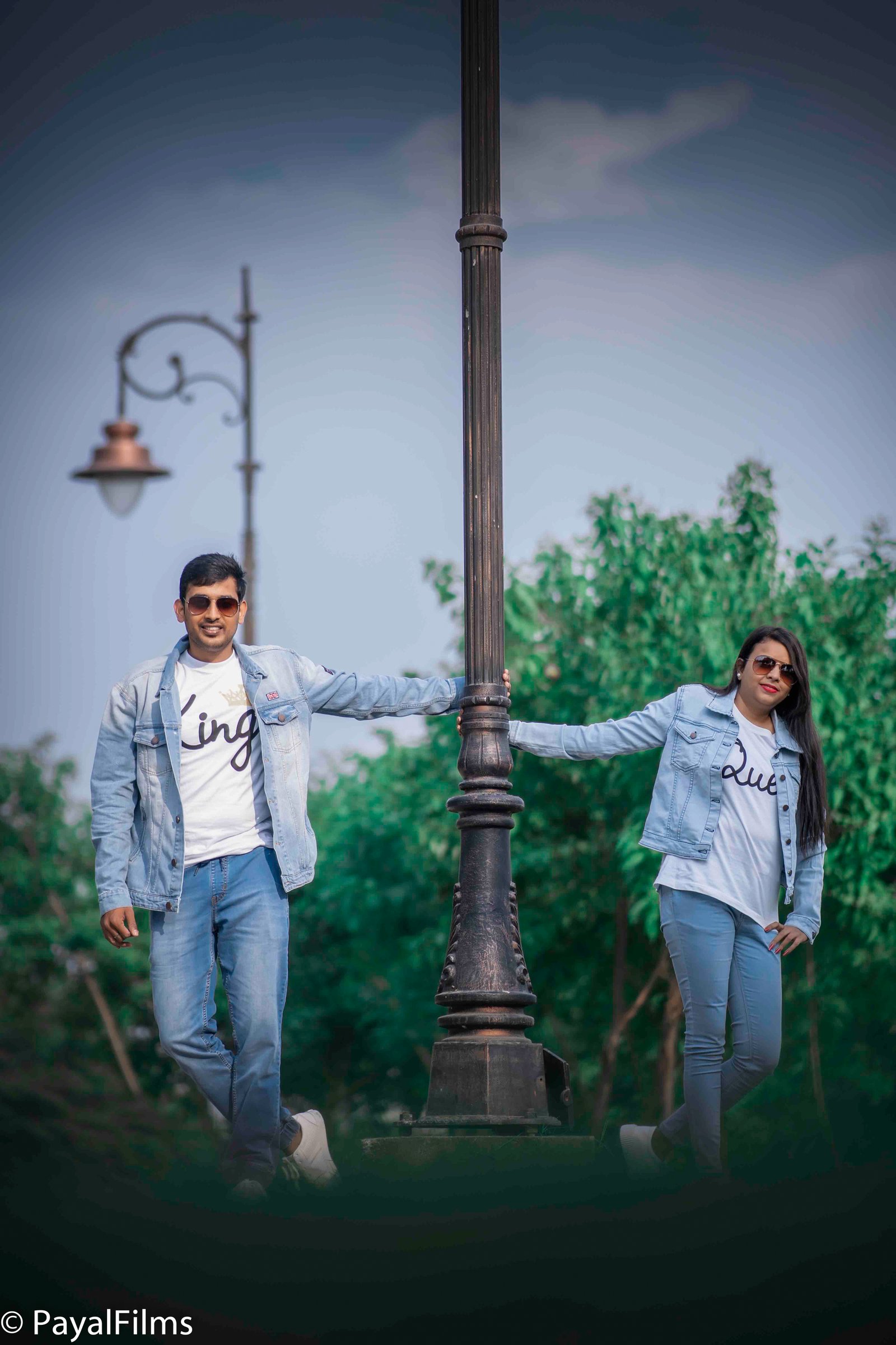 Couple in matching denim jackets and King-Queen t-shirts posing by a lamp post, captured by Payal Films in Khagaria.