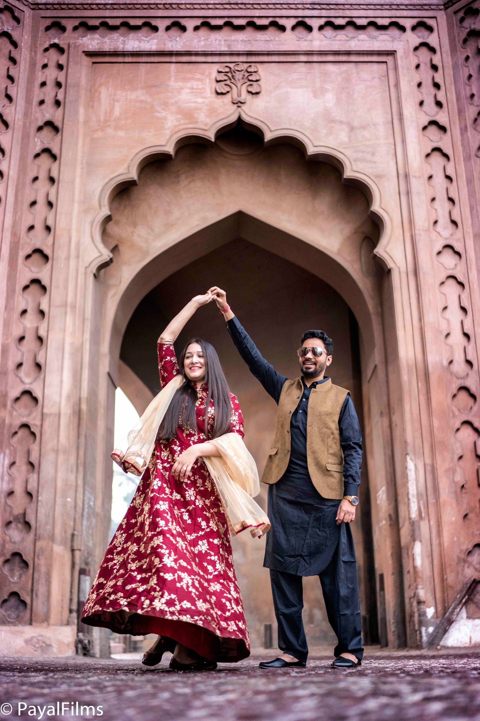 Joyful couple dancing outdoors under heritage archway during pre-wedding shoot by Payal Films Bihar
