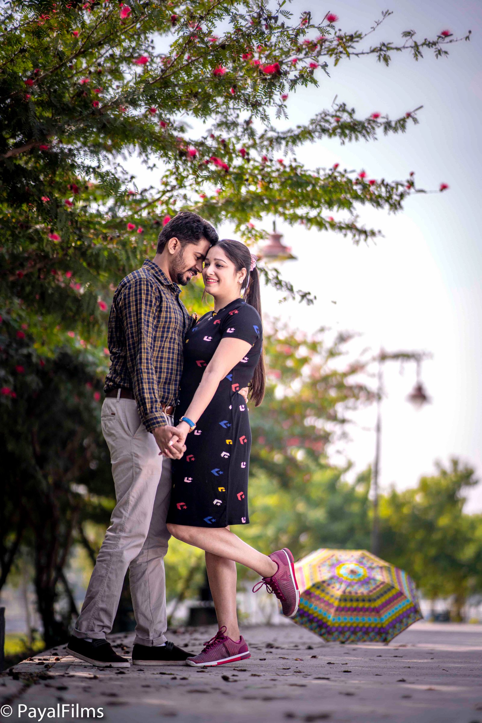 Joyful Indian couple holding fun props in maroon anarkali and blue Nehru jacket by Payal Films