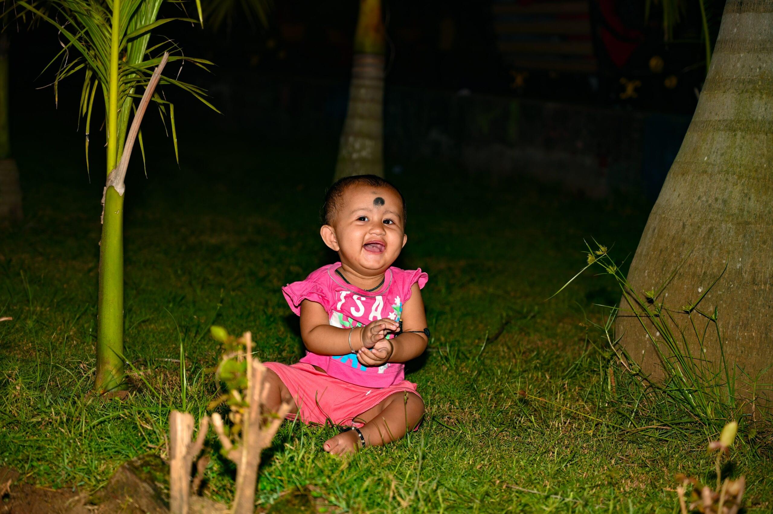 baby smiling pink outfit grass trees
