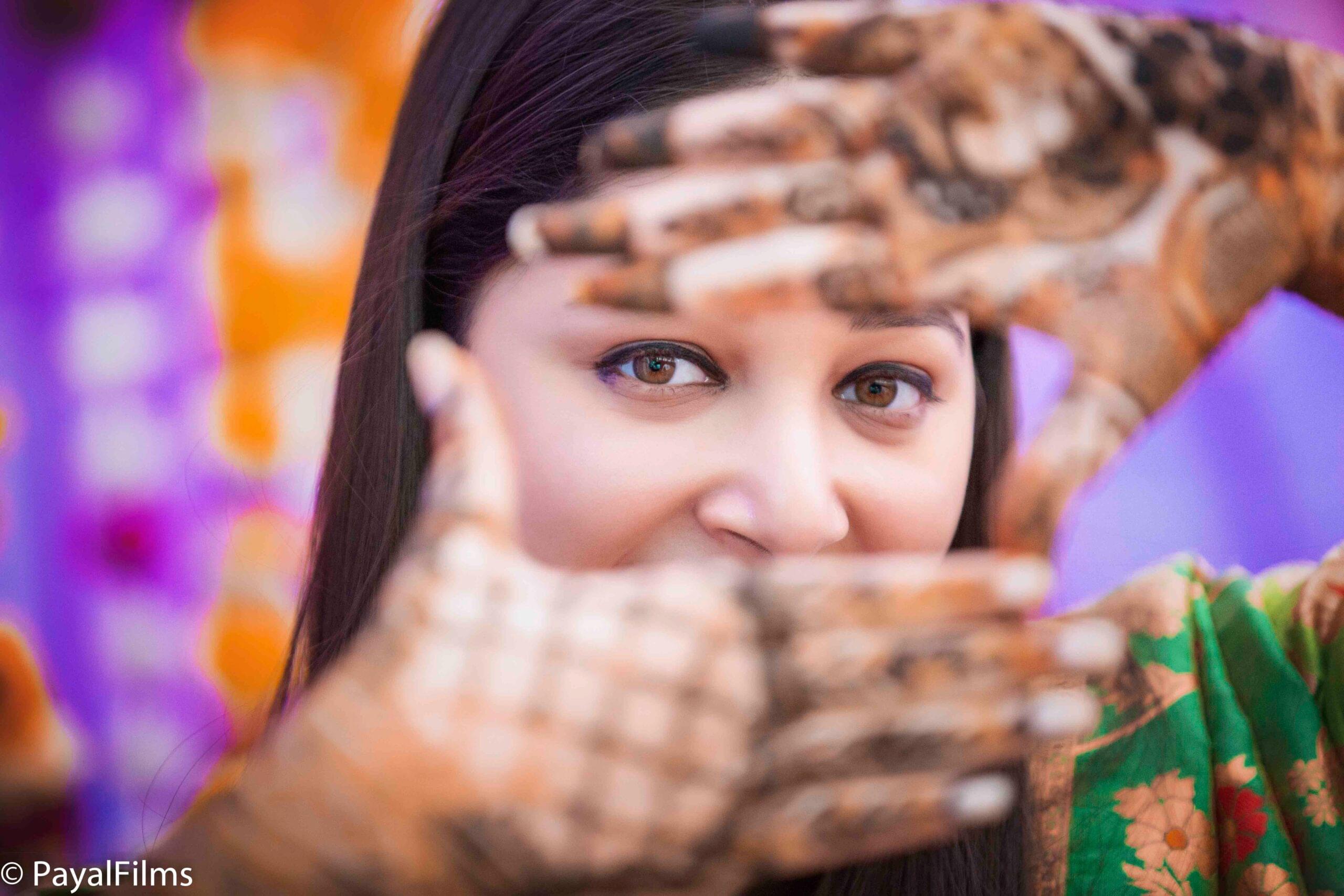 Payal Films creative bride portrait showing mehendi-decorated hands forming a frame, Bihar wedding