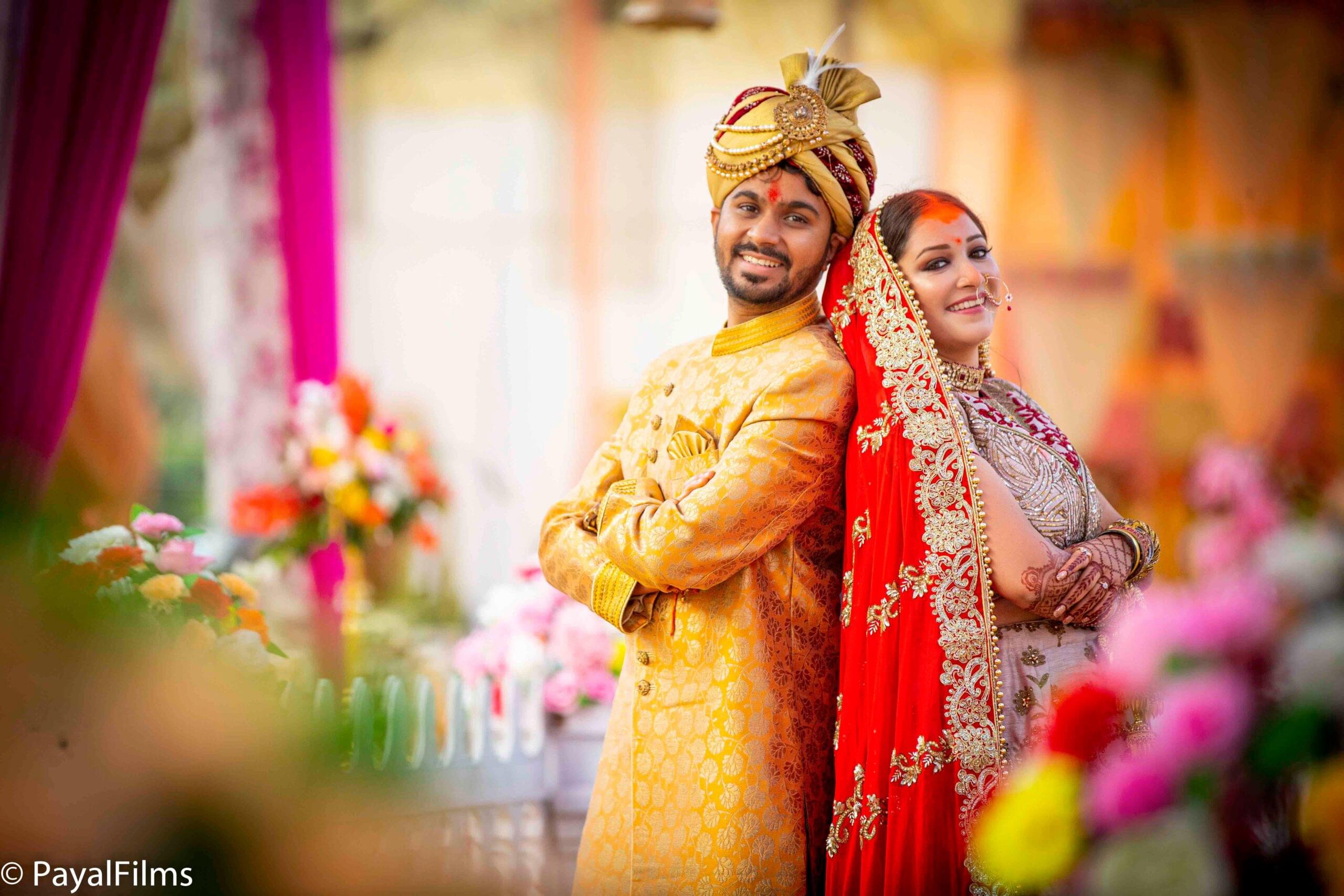 Payal Films wedding couple in gold sherwani and red lehenga posing back-to-back at Bihar ceremony