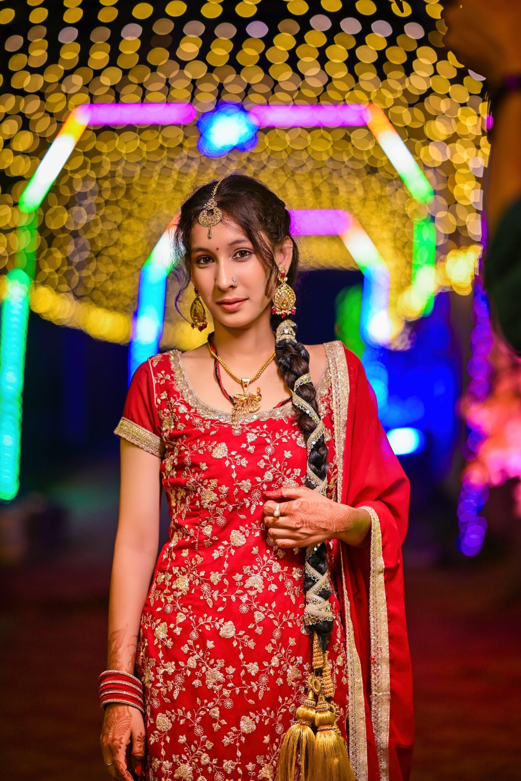 Stunning bridal portrait featuring ornate red lehenga, gold jewelry, and maang tikka captured by Payal Films