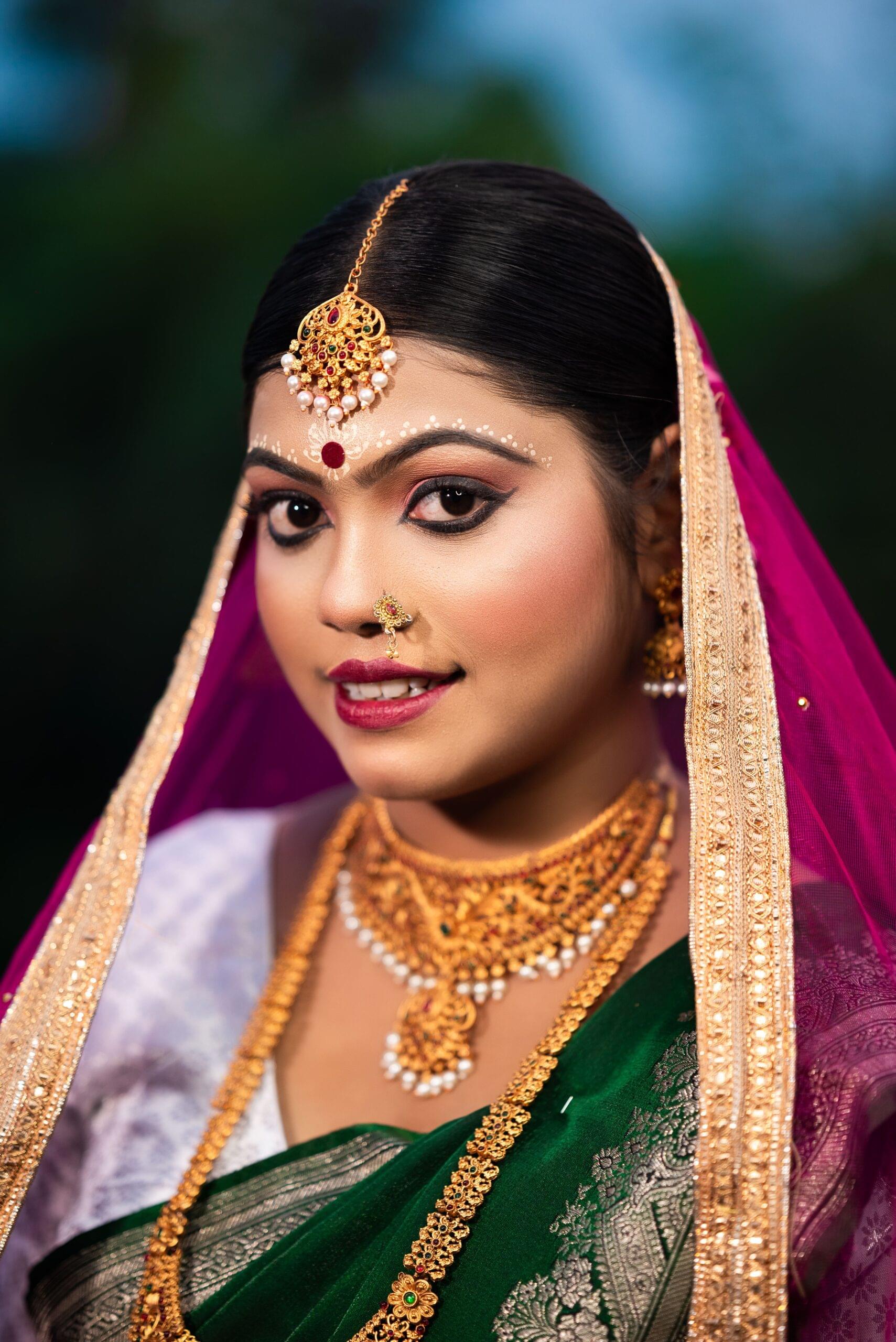 Indian Bengali bride in green saree and gold jewelry, adorned with a pink dupatta, photographed during her traditional wedding in Khagaria, Bihar.