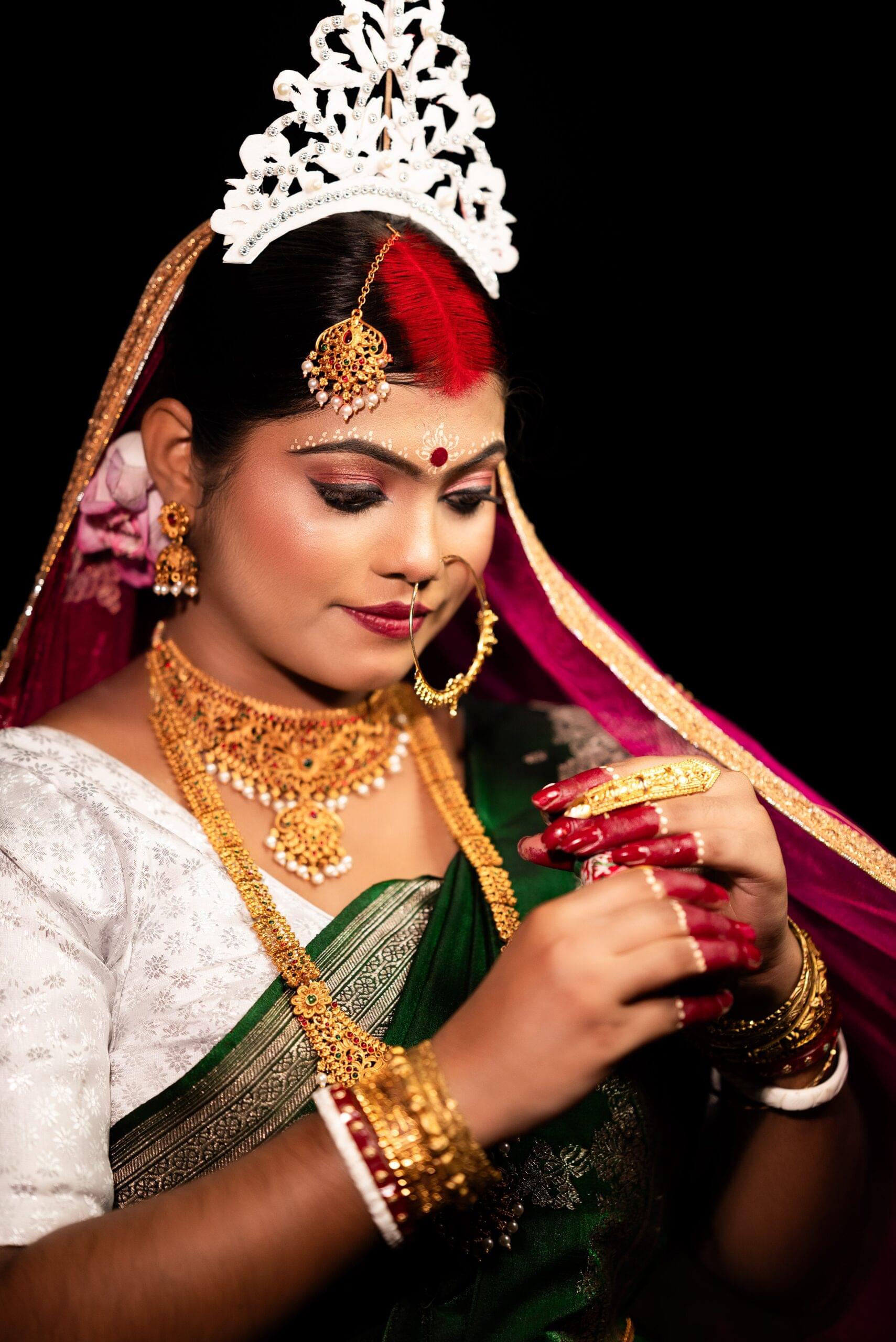 Indian Bengali bride in green saree, adorned with gold jewelry, white mukut crown, and shankha pola bangles—traditional wedding portrait, Khagaria, Bihar.